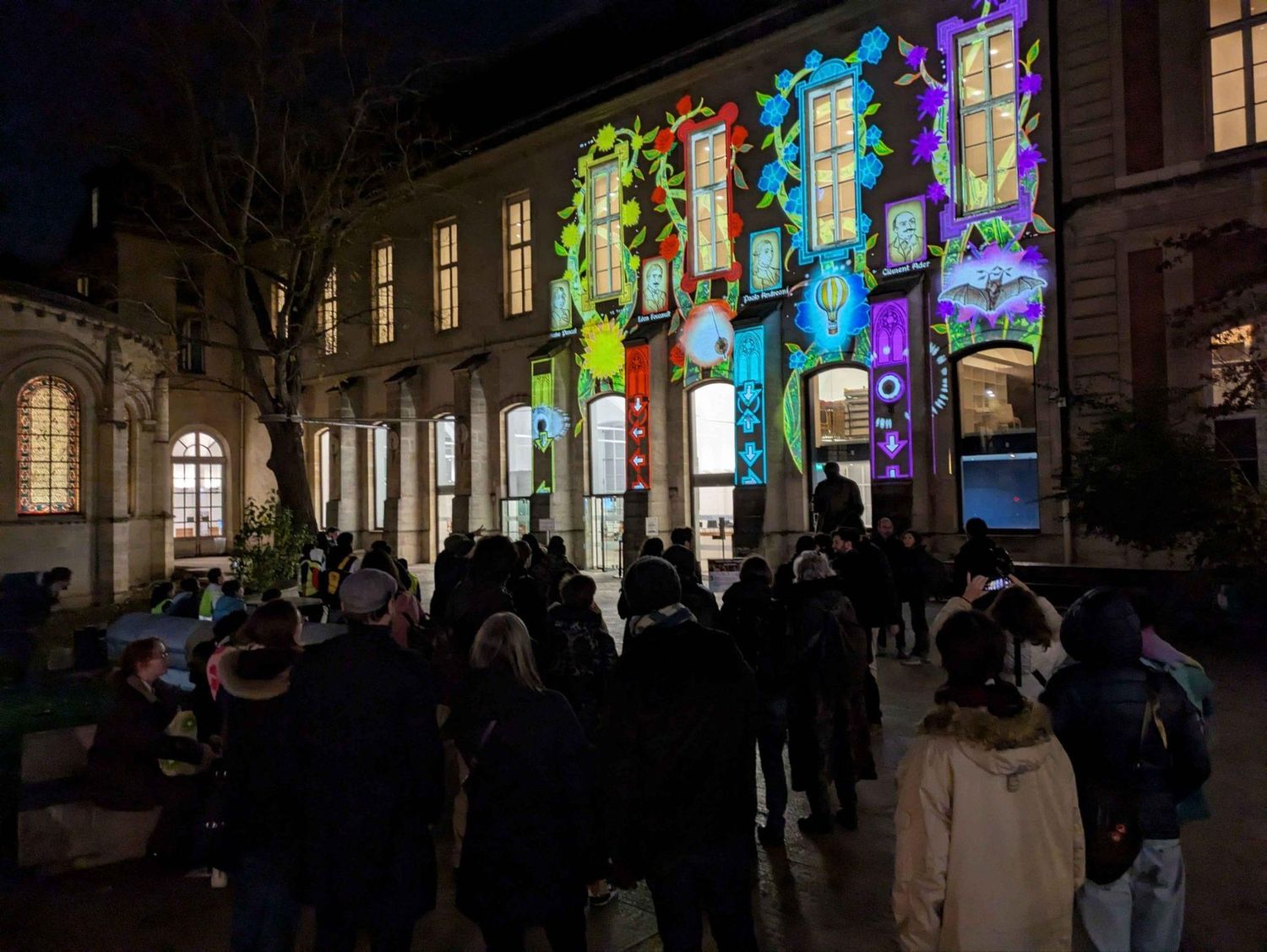 Déambulation nocturne du public le long de bâtiments couverts de projections.